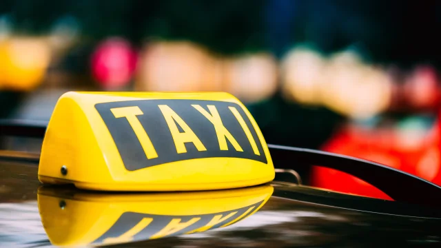 Yellow Taxi Sign On Roof Of Car.